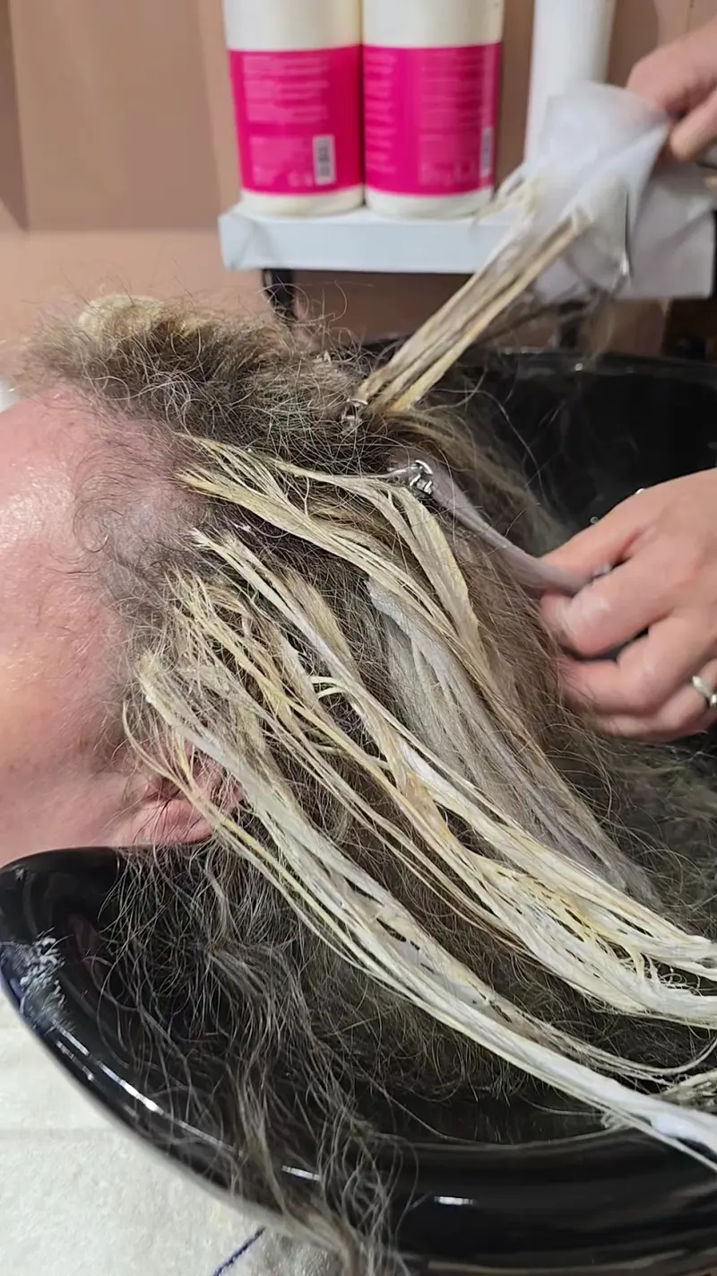 Blonde highlights being painted on in foils at the wash basin